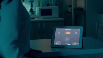 Jeune femme en utilisant intelligent Accueil application avec voix commander à tour sur le lumière par tablette. Dame en utilisant éclairage contrôle app dans moderne maison avec automatisation système contrôler Efficacité de énergie video