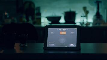 tablet met intelligent software geplaatst Aan tafel in keuken met niemand in, controlerend licht met hoog tech sollicitatie. kladblok met slim huis app in leeg huis automatisering systeem video