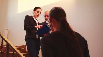 Businesswoman talking with corporate executive manager on staircase of business building looking on laptop. Professional successful entrepreneur in team working overtime in modern office stairs. video