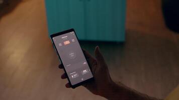 vicino su di uomo utilizzando voce attivato applicazione per girare su bulbi nel inteligente casa con automazione sistema. persona Tenere Telefono con moderno Software controllo luci nel Casa prima inizio Lavorando video