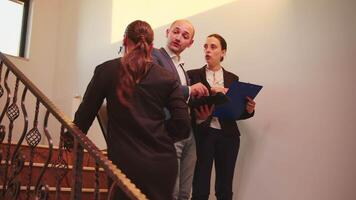 företag team gående på trappa möte kollegor arbetssätt använder sig av läsplatta, kvinna talande med företags- verkställande chef på trappa av företag byggnad. entreprenör överansträngning i kontor trappa. video