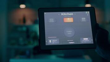 vicino su tiro di tavoletta con attivo inteligente casa applicazione trattenuto di uomo dando voce comando per interruttore su il luci. persona utilizzando alto tecnologia Software Lavorando a distanza a il computer portatile video