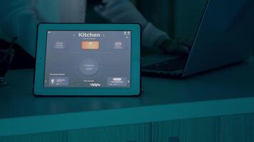weiblich Tippen auf Laptop Arbeiten von Zuhause mit Automatisierung Beleuchtung System mit Stimme kontrolliert auf Tablette Schalten auf Glühbirnen. Clever Gadget antwortet zu Befehle, Frau mit automatisiert App Software video