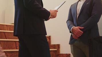 Close up of two business men in suit shaking hands standing on company stairs talking. Group of professional successful businesspeople working in modern financial workplace. video