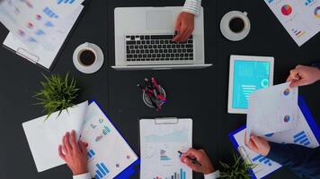 Top view of fast forward shot of people brainstorming financial statistics graphs planning next project using modern technology. Working in conference room with annual reports document on table. video