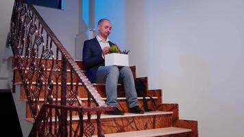 Desperate businessman being fired sitting on stairs in finance corporate company while colleagues leaving office building. Professional successful businesspeople working in modern financial workplace. video