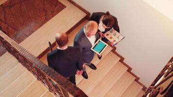 Top view of business team walking on stairs meeting colleagues working using tablet, woman talking with corporate executive manager on staircase holding clipboard. video