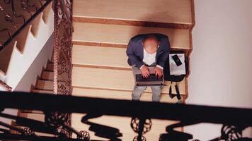 Top view of focused company manager typing on laptop doing research sitting on stair in corporate office. Business man entrepreneur overwork at deadline project in modern financial building. video