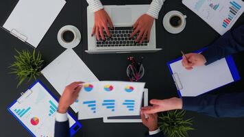 Directly above view of business people working with financial documents and presentation on tablet at office desk, planning project taking notes. Teamwork brainstorming on copy space, flat lay concept video