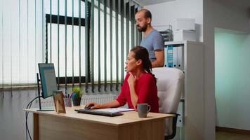 ispanico donna chiede collago per Aiuto seduta nel davanti di pc nel moderno ufficio. squadra Lavorando nel professionale posto di lavoro nel personale aziendale azienda digitando su computer tastiera guardare a del desktop video