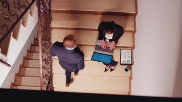Top view of business woman overworking with laptop sitting on stairs of business center analysing financial raports while colleagues leaving office building. Executive manager doing overtime at job video