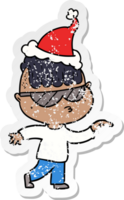 hand drawn distressed sticker cartoon of a boy wearing sunglasses pointing wearing santa hat png