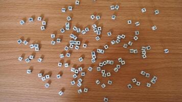 alphabet white beads blocks with letters in heart, random letters around, top view wooden background backdrop photo