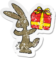 retro distressed sticker of a cartoon rabbit with christmas present png