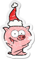 cheerful sitting pig hand drawn distressed sticker cartoon of a wearing santa hat png