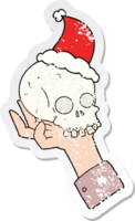 hand drawn distressed sticker cartoon of a hand holding skull wearing santa hat png