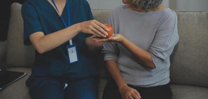 Happy young female nurse provide care medical service help support smiling old grandma at homecare medical visit, lady carer doctor give empathy encourage retired patient sit on sofa at home hospital photo