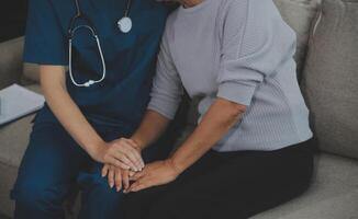 Female caregiver doing regular check-up of senior woman in her home. photo