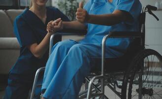 Doctor giving hope. Close up shot of young female physician leaning forward to smiling elderly lady patient holding her hand in palms. Woman caretaker in white coat supporting encouraging old person photo