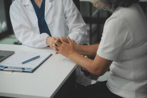 African female doctor hold hand of caucasian woman patient give comfort, express health care sympathy, medical help trust support encourage reassure infertile patient at medical visit, closeup view. photo