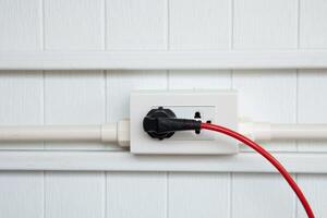 An electric plug with a red cable in the socket. photo