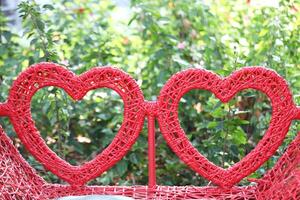 Red heart shaped braided wicker with green leaves background photo