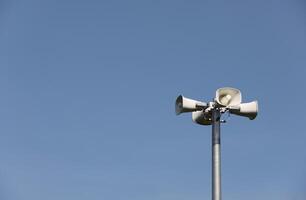 Whire horn speaker in the park with clear blue sky background. photo