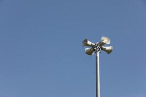 Whire horn speaker in the park with clear blue sky background. photo