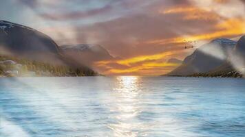 une tranquille le coucher du soleil plus de une calme lac, encerclé par majestueux montagnes. le d'or des rayons de le Soleil jeter une réflexion sur le eau, création une serein atmosphère. video