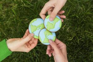 Earth Day concept. Hands hold gingerbread in the shape of the Earth. Care for the environment. photo