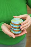 Earth Day concept. Stack of cookies in the shape of the Earth in female hands. photo
