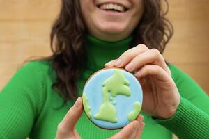 Earth Day concept. Gingerbread in the shape of a planet in the hands of a woman. photo