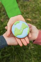 Earth Day concept. Hands hold gingerbread in the shape of the Earth. Care for the environment. photo