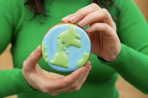 Earth Day concept. Gingerbread in the shape of a planet in the hands of a woman. photo