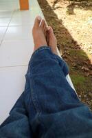 a pair of legs of a man wearing blue trousers with a ceramic floor in the background photo