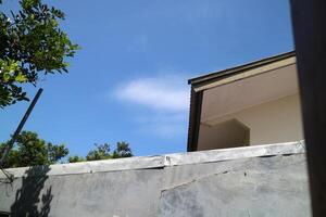 view of a house roof and walls with a view of the bright blue sky photo