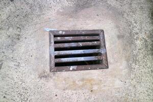 an iron gutter cover, with a rust color. Box shaped. on a concrete road photo