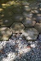 outdoor concrete paving floor with a hexagon shape, filled with moss, with a little gravel beside it photo