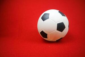 a small white and black toy rubber ball. Red background photo