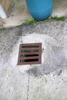 an iron gutter cover, with a rust color. Box shaped. on a concrete road photo