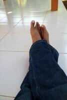 a pair of legs of a man wearing blue trousers with a ceramic floor in the background photo