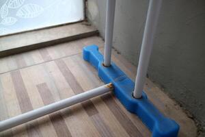 The foot of a clothesline outside the house. white and blue, made of hollow iron and plastic photo