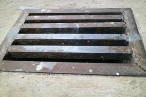 an iron gutter cover, with a rust color. Box shaped. on a concrete road photo