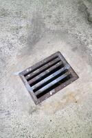 an iron gutter cover, with a rust color. Box shaped. on a concrete road photo