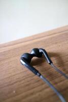 a pair of headsets with cables. black, placed on a table with a wooden motif photo