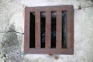 an iron gutter cover, with a rust color. Box shaped. on a concrete road photo