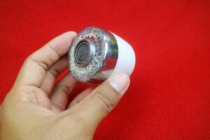 hand holding a head of the sink drain. used condition. red background photo