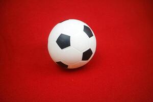 a small white and black toy rubber ball. Red background photo