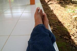 a pair of legs of a man wearing blue trousers with a ceramic floor in the background photo