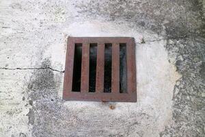 an iron gutter cover, with a rust color. Box shaped. on a concrete road photo